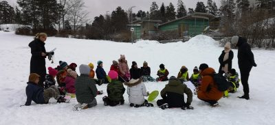 Valokuvassa oppilaita satupiirissä ulkona lumihangessa.